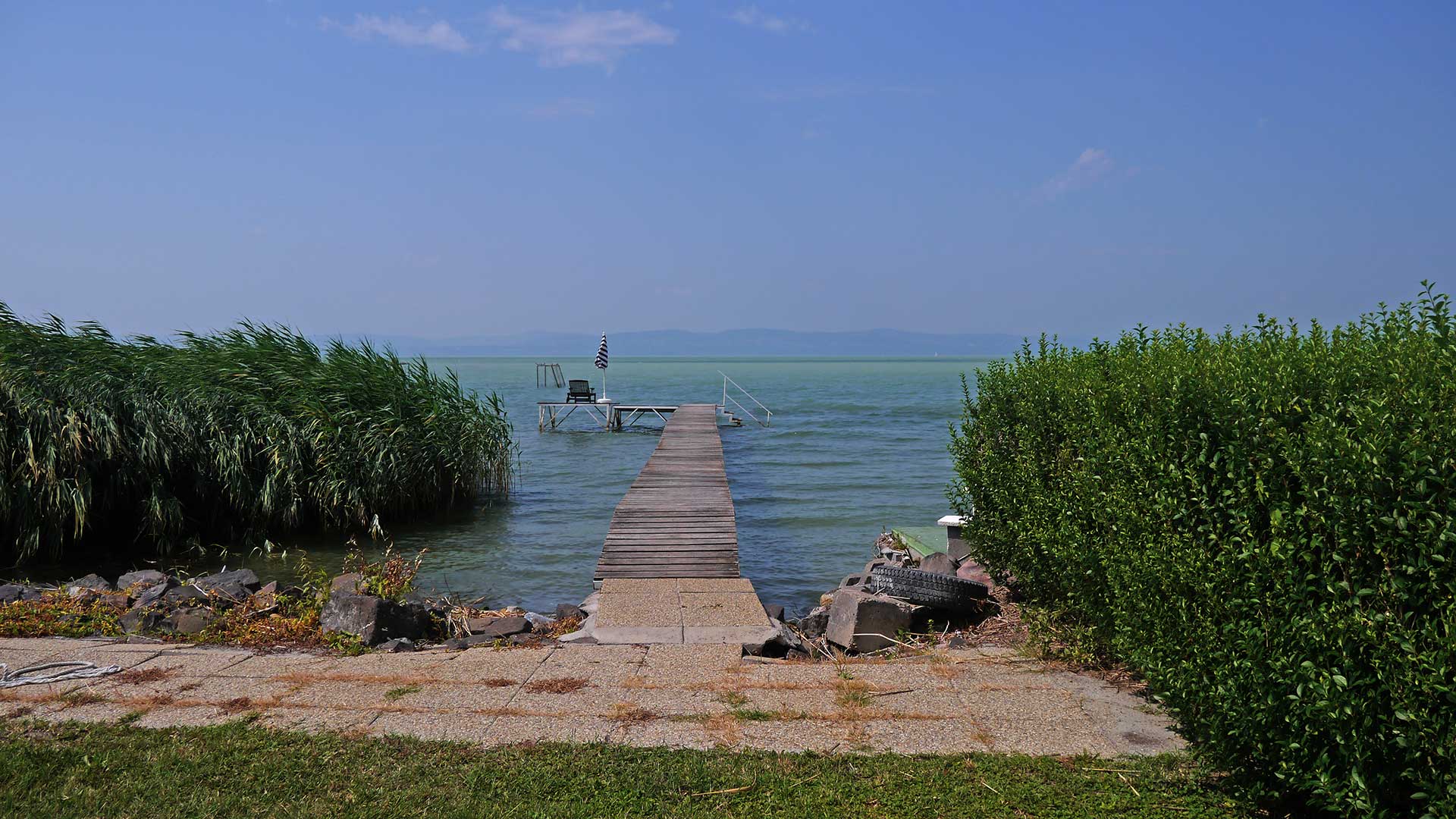 A képen, egy valamikor eladó vízparti jellegű nyaraló látszik a Balaton partján, saját stéggel